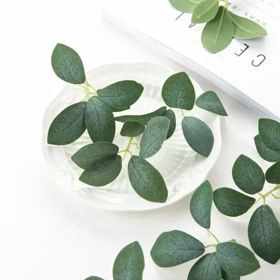 A cluster of deep green silk 5leaf artificial roses with realistic veins on a white ceramic plate for wedding decor