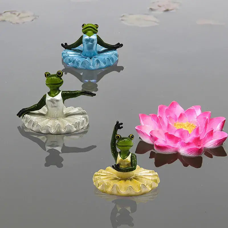Three miniature frog figurines in ballet tutus with green and blue accents near a pink lotus flower for decorbites garden water floating