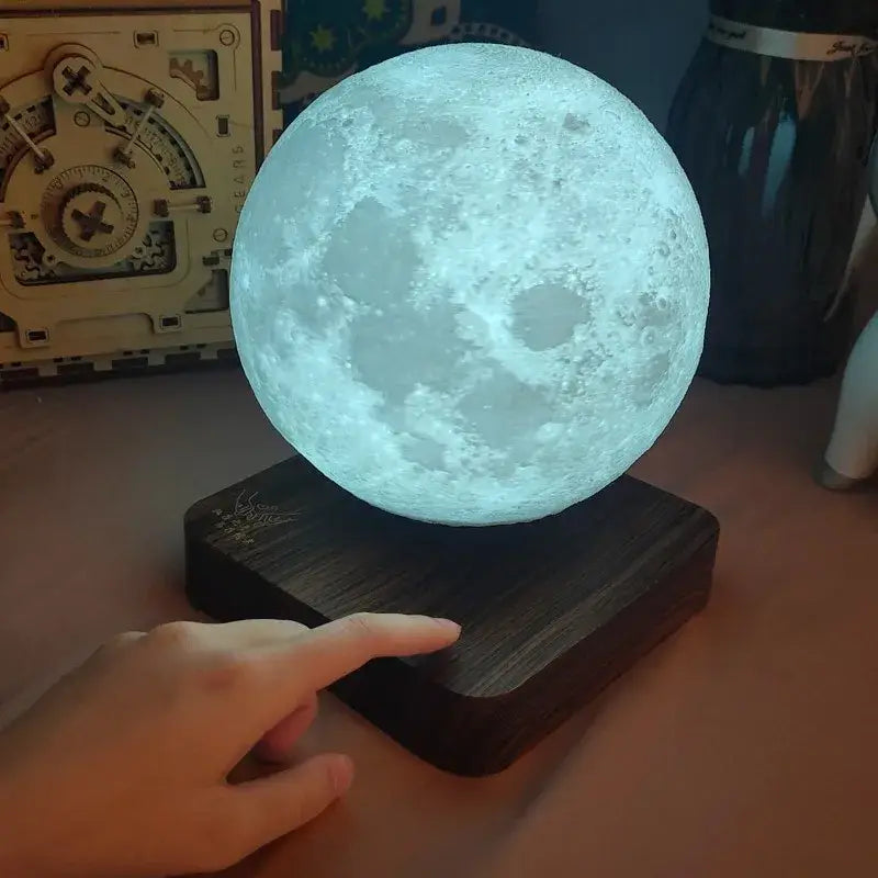 A decorbites levitating moon lamp with realistic cratered surface and soft blue light on a dark wooden base for bedroom decor