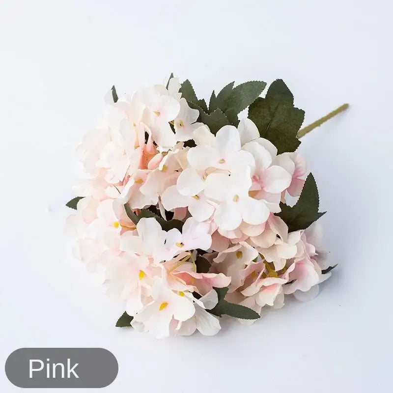 A delicate pink and white artificial hydrangea branch decor with soft petals and dark green leaves by decorbites hydrangea branch decor