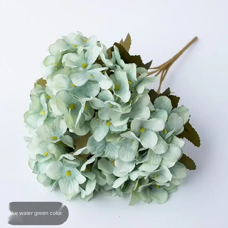 A delicate cluster of decorbites hydrangea branch decor in soft green with yellow centers and realistic leaf accents