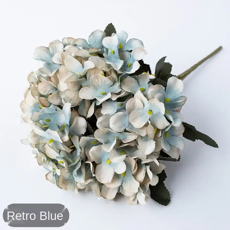A delicate decorbites hydrangea branch decor featuring realistic blue artificial petals and dark green leaves for wedding decor