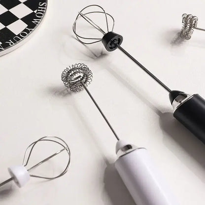 Two rechargeable electric milk frother mixers with sleek black and white handles and silver and black wire whisk attachments