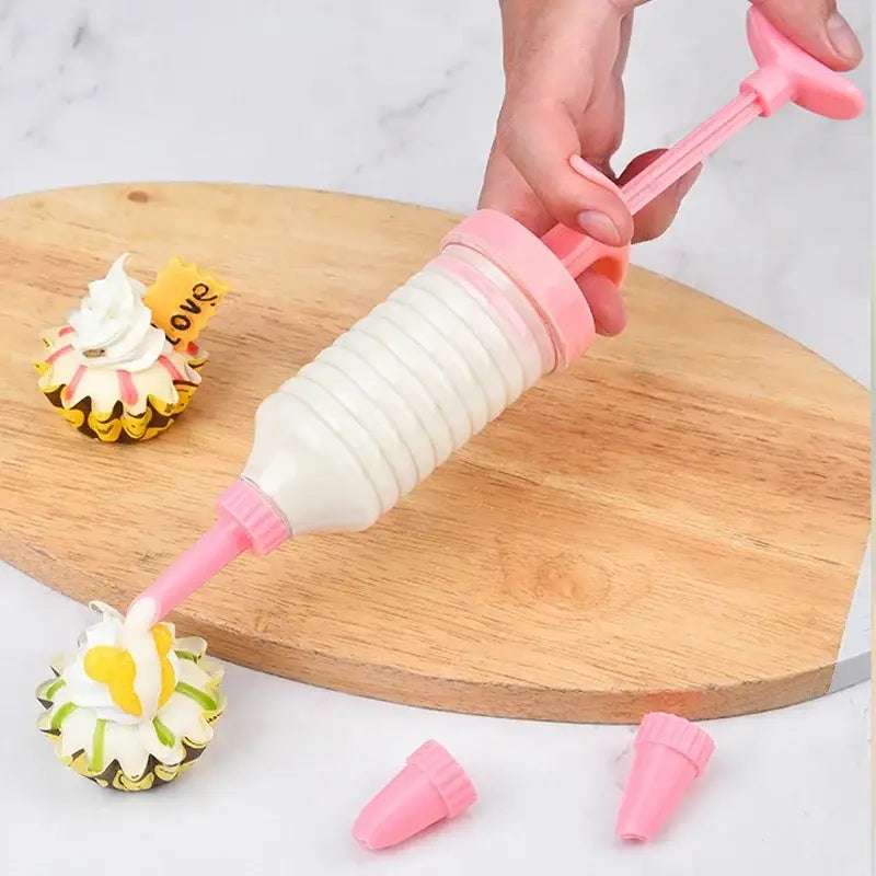 Pink plastic cream cake press with ribbed barrel and interchangeable nozzles for decorbites cookie cream cake kit