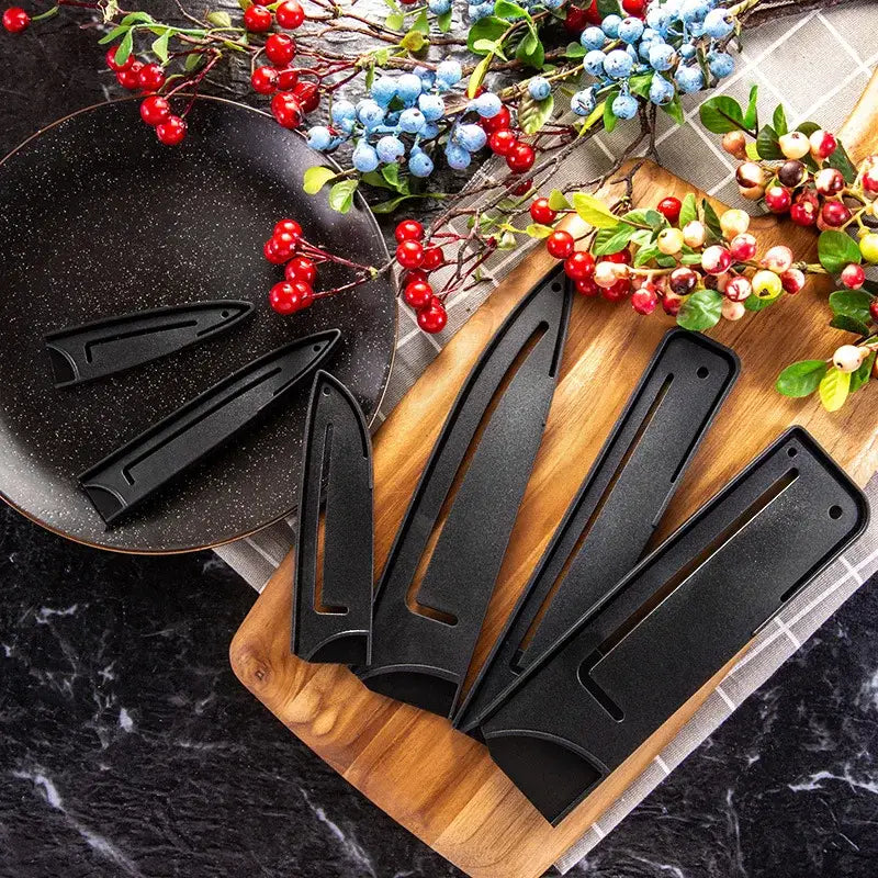 Black plastic knife blade protector covers with matte finish and ergonomic design on wooden cutting board