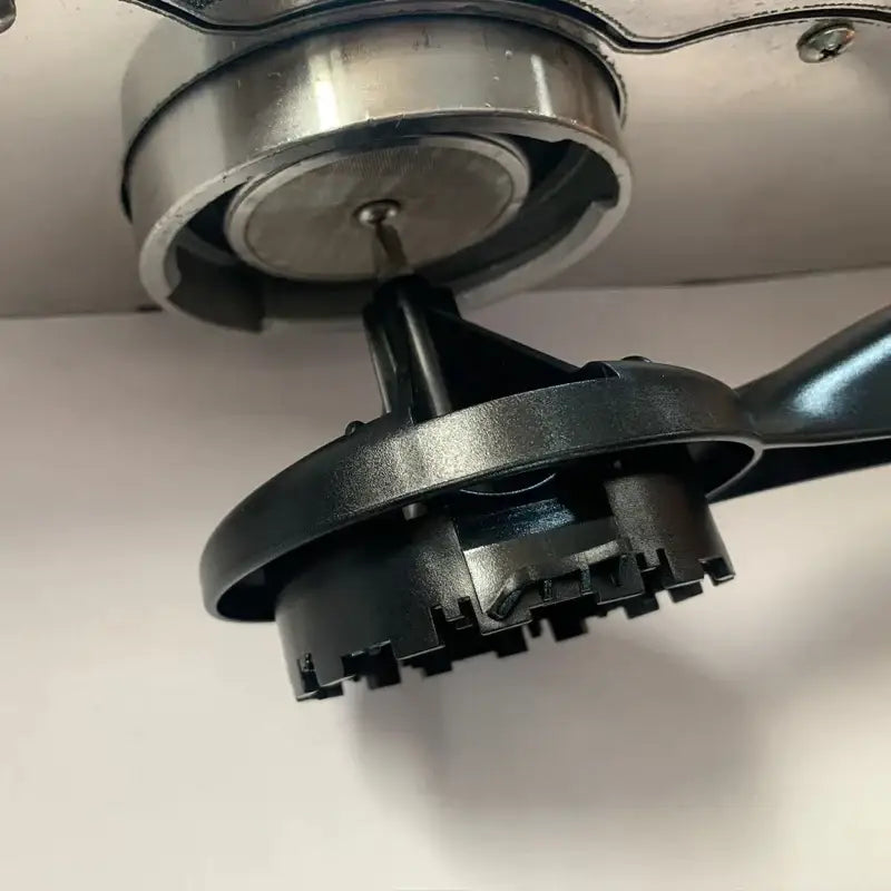 Black plastic and metallic bicycle chain tool with circular handle shown alongside red and white espresso machine cleaning brush