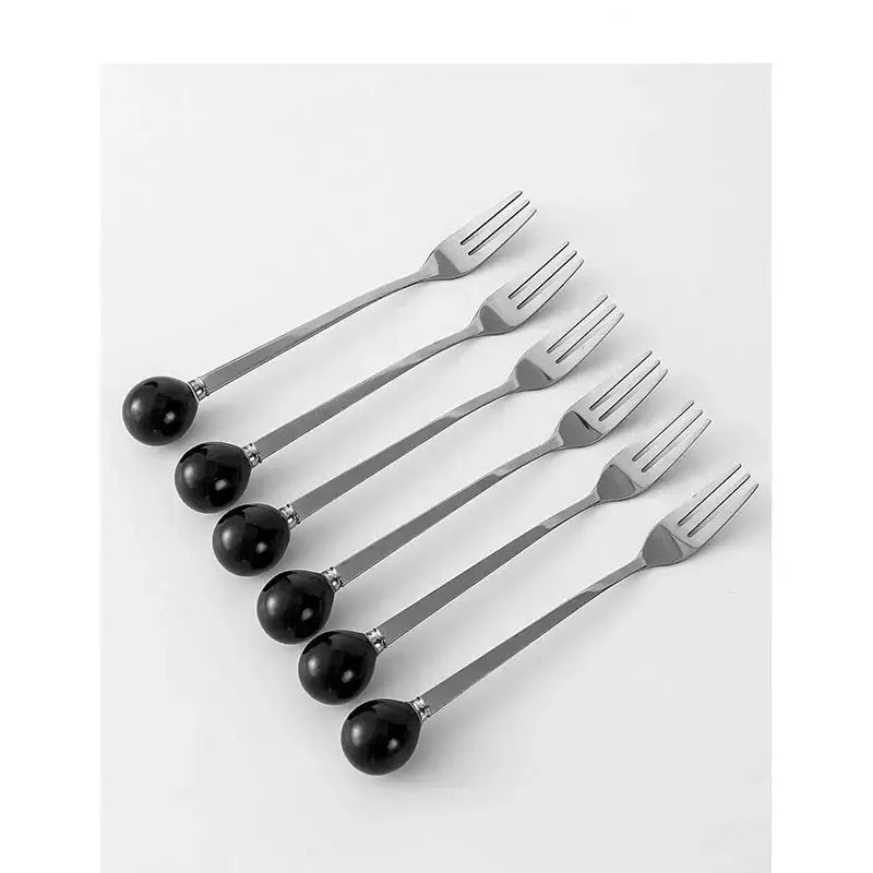 Set of six stainless steel forks with polished black spherical handles beside a red ceramic boot desk organizer box for office storage