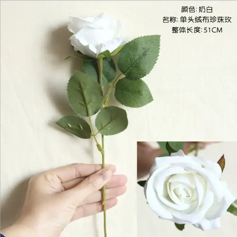 A delicate white fabric rose with green leaves and slender stem from decorbites dried roses artificial flowers wedding decor