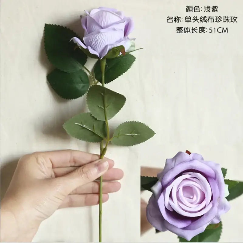 A delicate light purple artificial rose with layered petals and green leaves from decorbites dried roses wedding decor