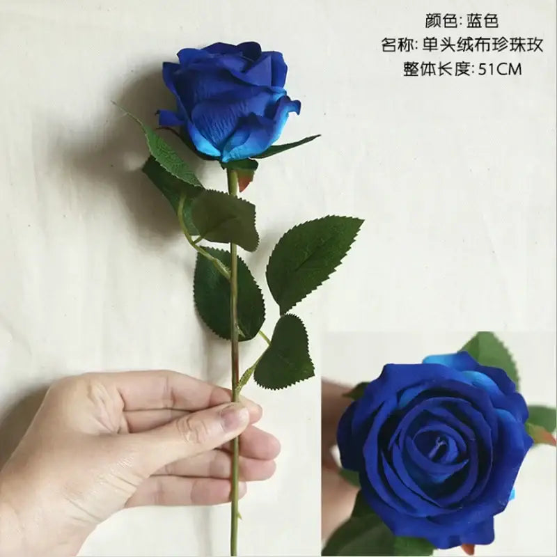 A vibrant royal blue artificial rose with textured fabric surface and green leaves in decorbites dried roses wedding decor