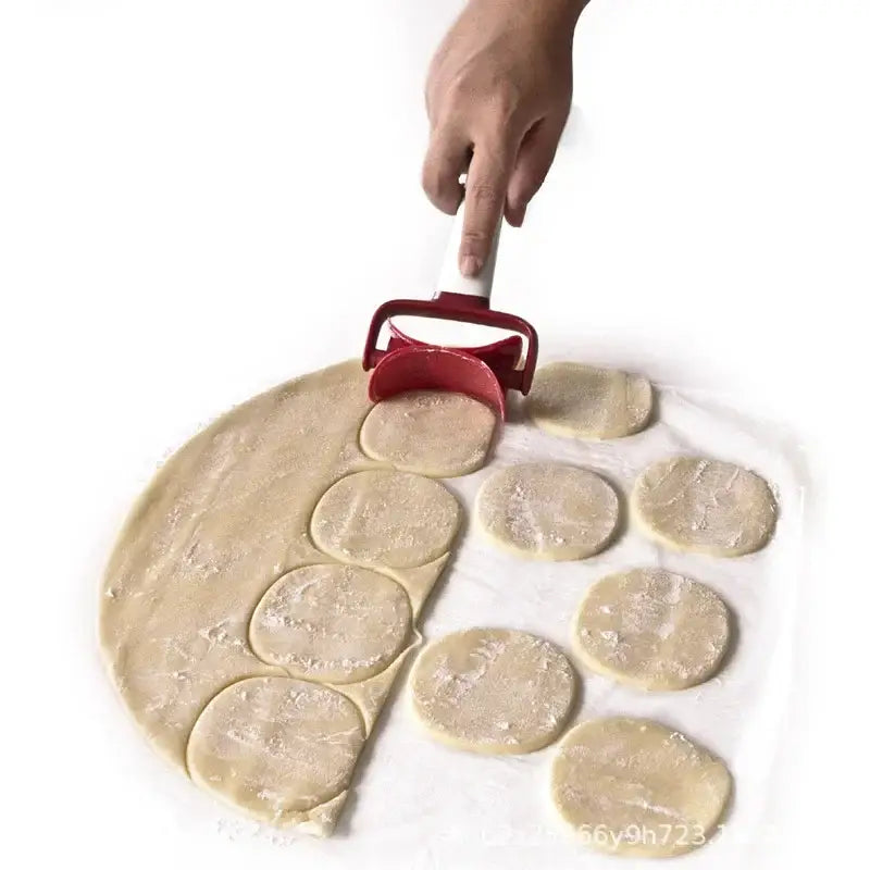 Red silicone spatula dough press cutter with white handle pressing down to cut circular shapes from dough