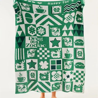 Green and white decorbites knitted blanket featuring a grid of dragons stars coffee cups and zodiac symbols for bedroom decor
