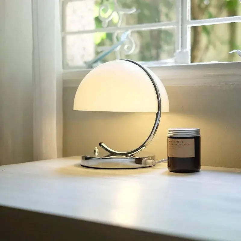 A sleek chrome decorbites glass table lamp with a frosted glass dome shade for retro amber bedroom decor