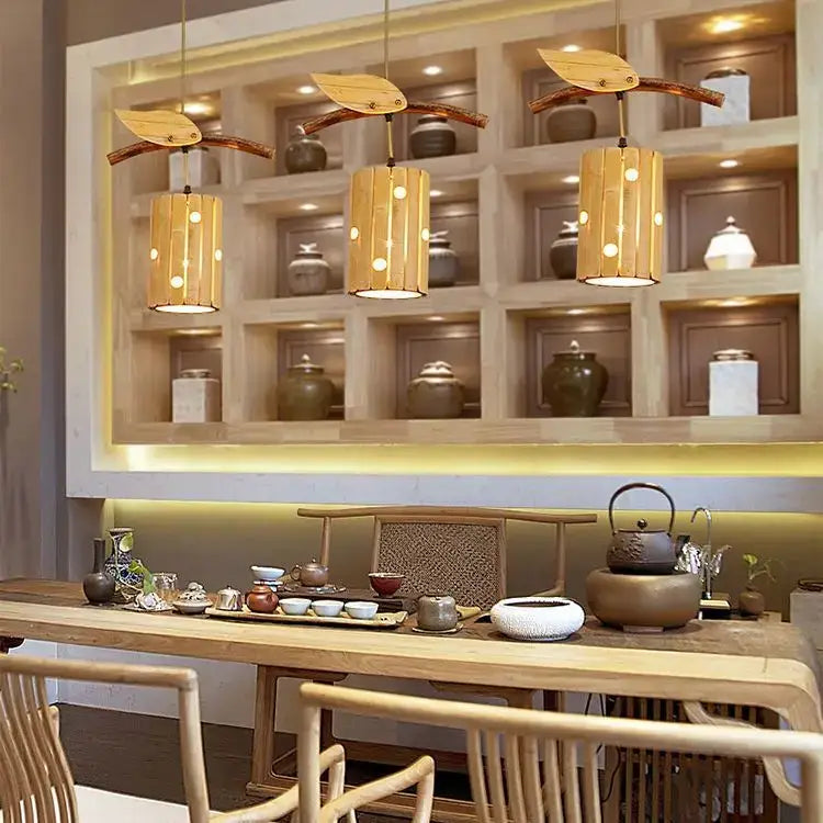 Three hanging bamboo art chandelier pendant lights with leaf-shaped wooden tops and circular cutout shades for dining room