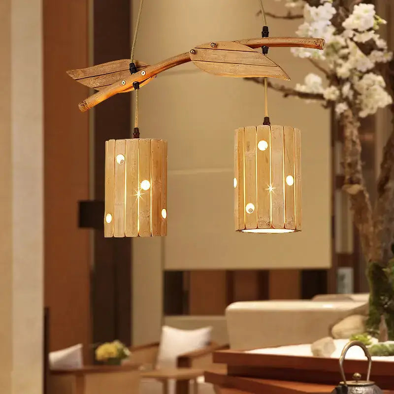 Retro bamboo art chandelier featuring a natural wood branch design with two slatted bamboo lanterns emitting warm light