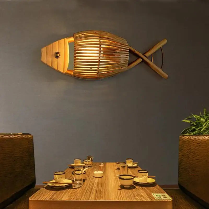 A golden bamboo fish wall lamp with warm glowing light ideal for retro living room slatted wood decor by decorbites bamboo fish