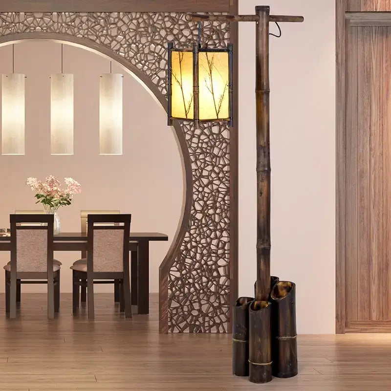 A rustic bamboo weave floor lamp with a warm amber-lit lantern featuring delicate branch cutouts for zen living rooms