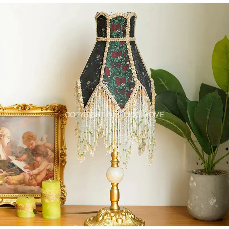 Antique retro table lamp with black floral roses shade, gold trim, beaded fringe, brass base, and white marble accent