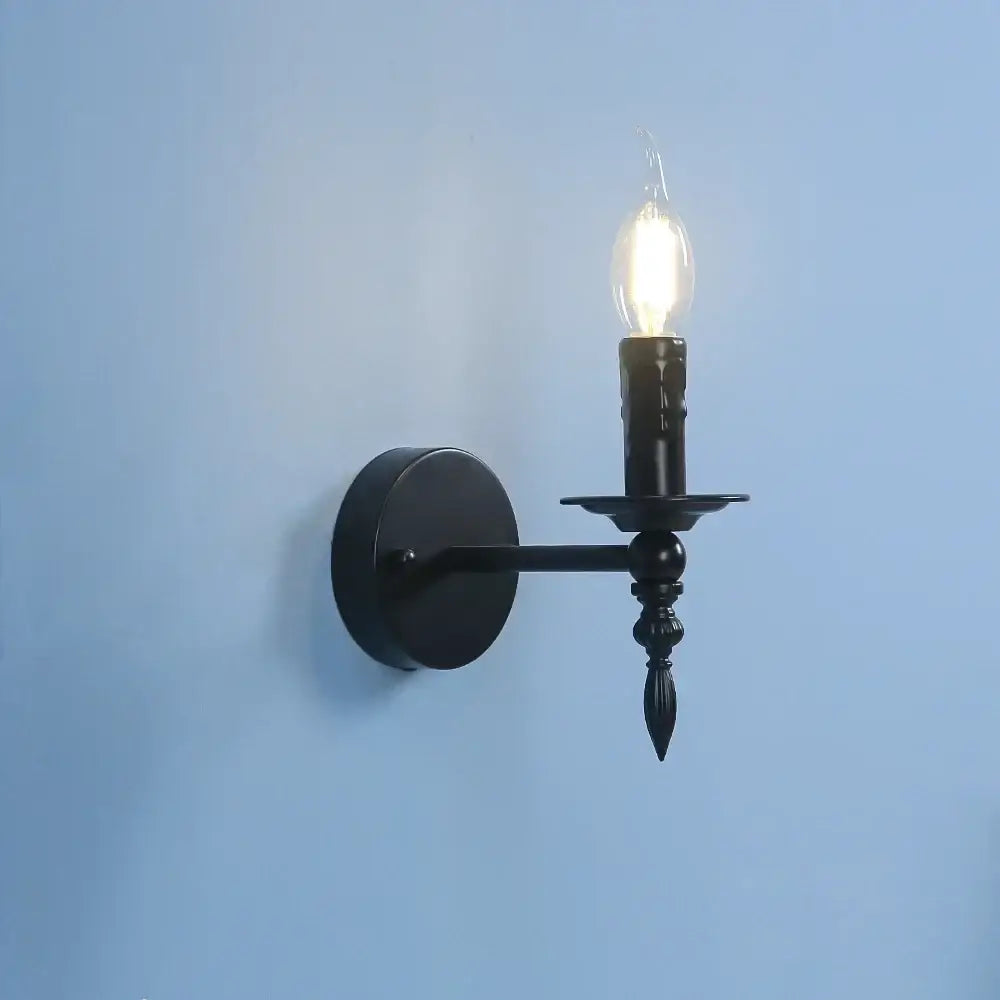 Retro black iron art wall lamp featuring a black wrought iron candlestick-style wall sconce with a glowing filament bulb