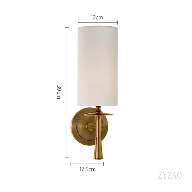 A sleek brass wall lamp with a cylindrical off-white fabric shade for bedroom decorbites brass wall lamp