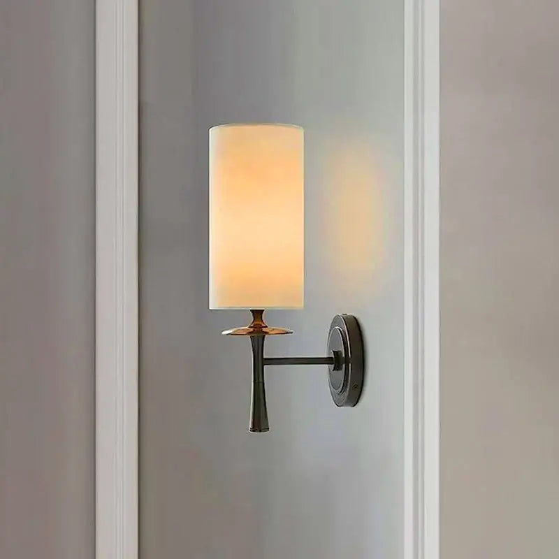 Warm-toned fabric cylindrical lampshade wall lamp with sleek black metal arm and decorbites brass wall lamp accent