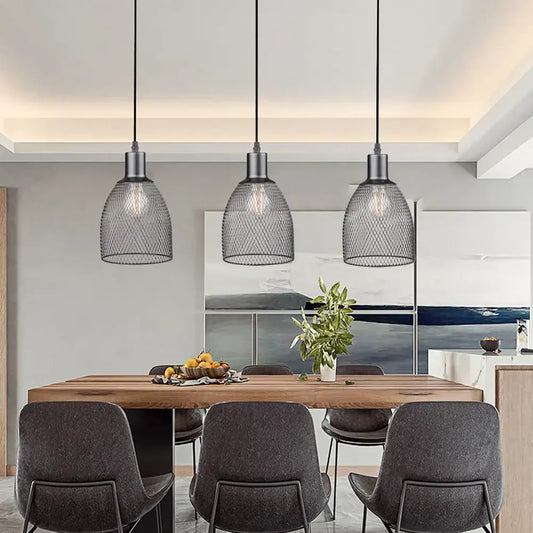 Three black metal decorbites cage bell pendant lights hang above a wooden dining table as pendant light decor