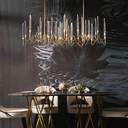 Gold-toned chandelier with slender glass arms and warm bulbs paired with retro black rattan chair and puma cushion decorbites crystal candle