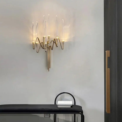 Gold-toned crystal candle wall sconce with five transparent glass candle-like arms and wavy metallic base for decorbites candle wall sconce