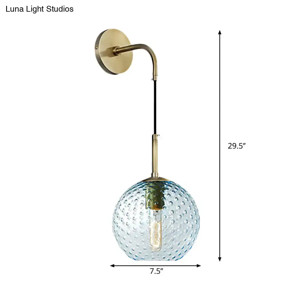 Retro blue glass globe wall lamp with textured bubble surface in yellow blue hanging from brass arm for bedroom use