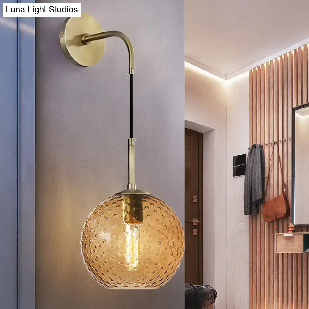 Brass-finished wall sconce with textured amber glass globe for bedroom pink yellow blue light accents