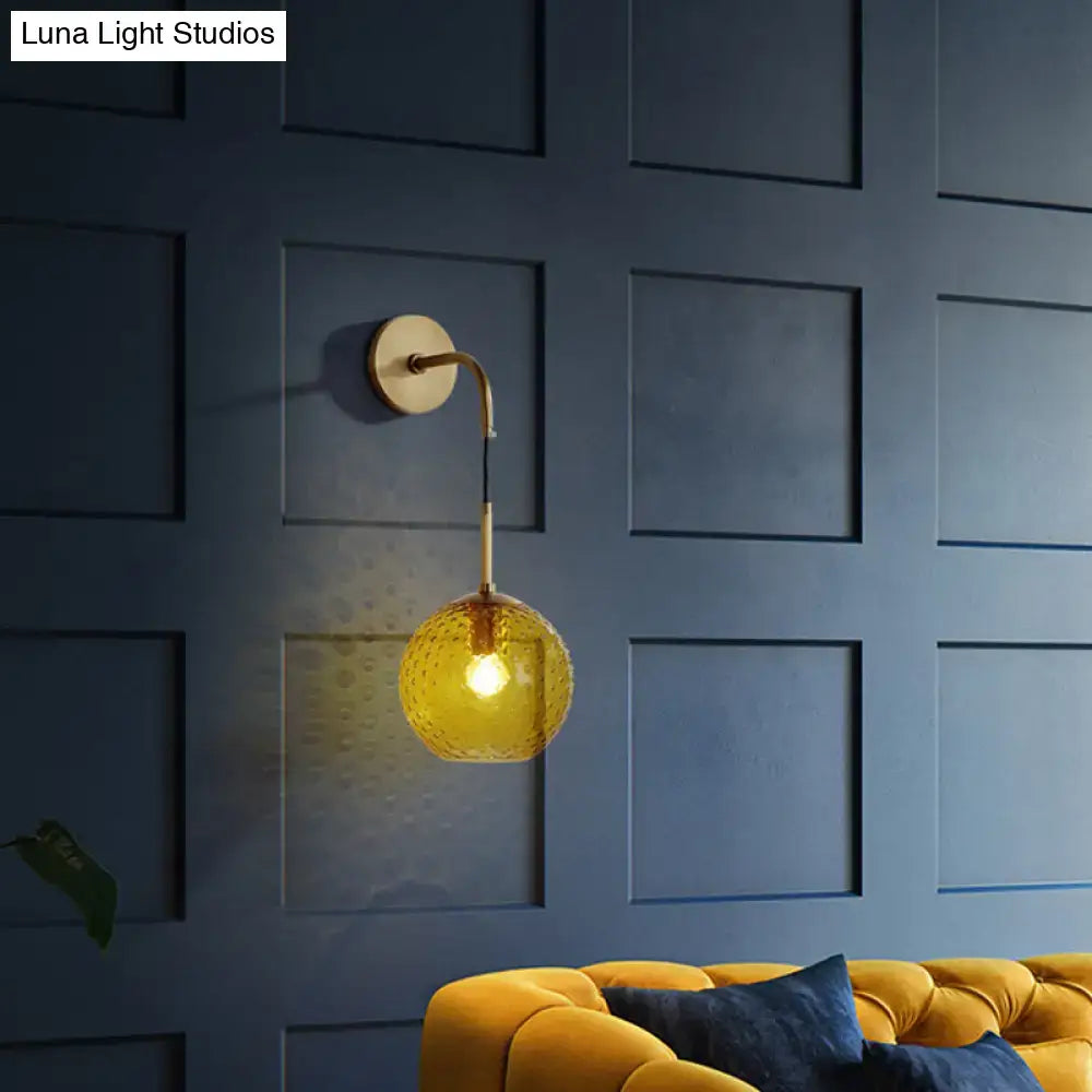 Gold-toned wall sconce with textured amber glass globe for pink yellow blue retro bedroom lighting decor