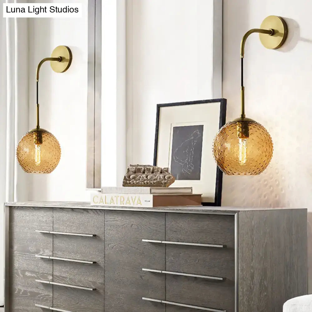 Gold-toned wall sconces with textured amber glass globes and brass arms for pink yellow blue bedroom lighting