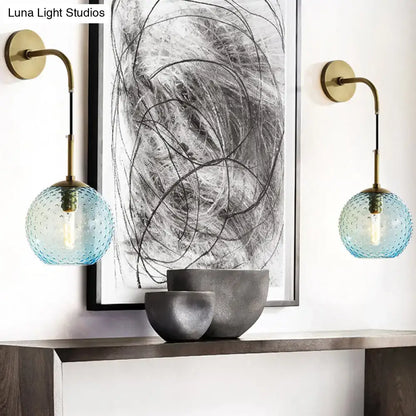 Retro blue glass globe wall lamp with brass fixtures featuring textured blue glass for pink yellow blue lighting ambiance