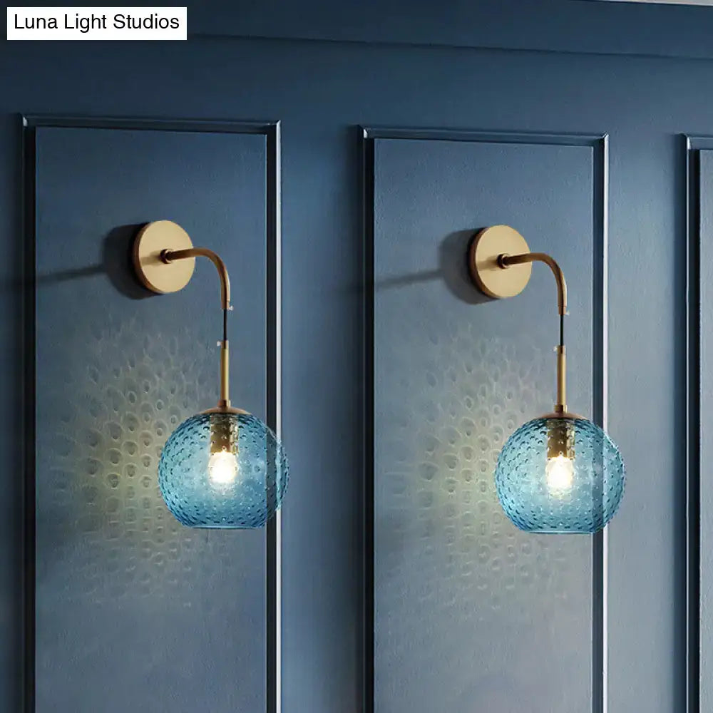 Retro blue glass globe wall lamp with brass arms and circular backplates featuring pink yellow blue lighting effects
