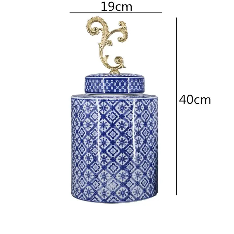 A tall cylindrical retro blue and white porcelain covered vase jar with a decorative gold-toned metal finial lid