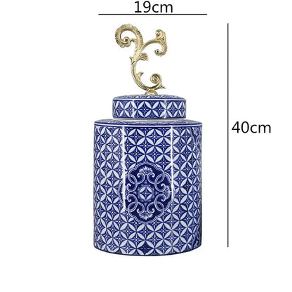 A tall cylindrical retro blue and white porcelain covered vase jar with an ornate gold metal lid finial for living room storage
