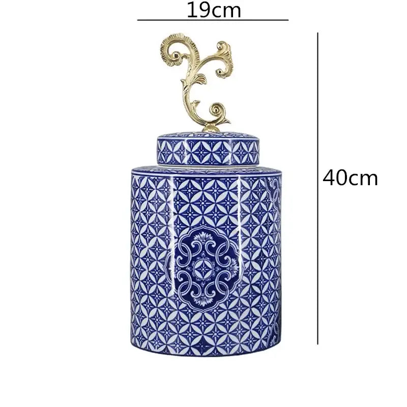 A tall cylindrical retro blue and white porcelain covered vase jar with an ornate gold metal lid finial for living room storage