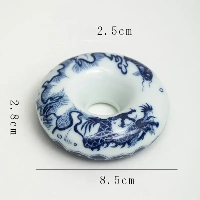 A delicate white porcelain incense burner with blue dragon motifs and central hole, part of a retro blue and white teacup tray set