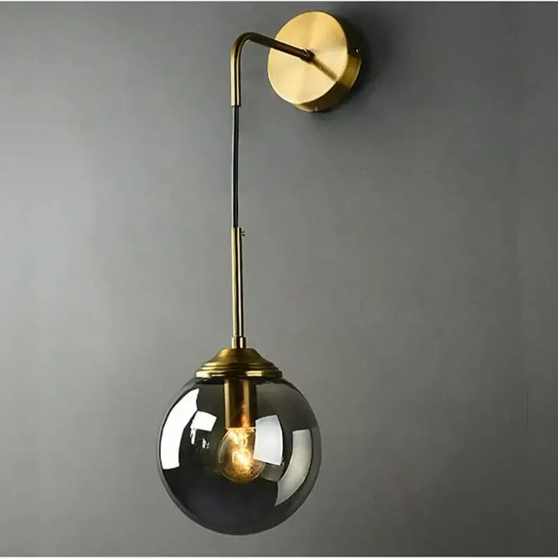 Brass finished wall lamp with sleek curved arm and dark smoked decorbites glass ball led globe for bathroom sconce
