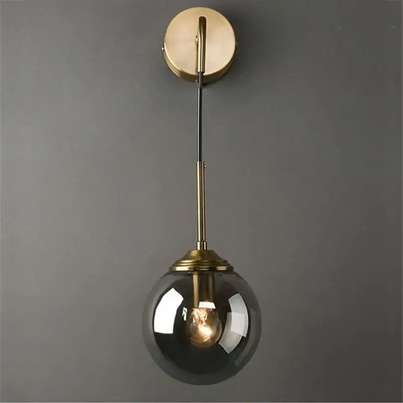 A sleek retro brass wall lamp with a decorbites glass ball led and smoked glass globe bathroom sconce