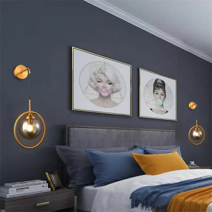 Gold-toned retro brass and amber decorbites glass ball wall lamp with glass ball led shades hangs symmetrically by bed