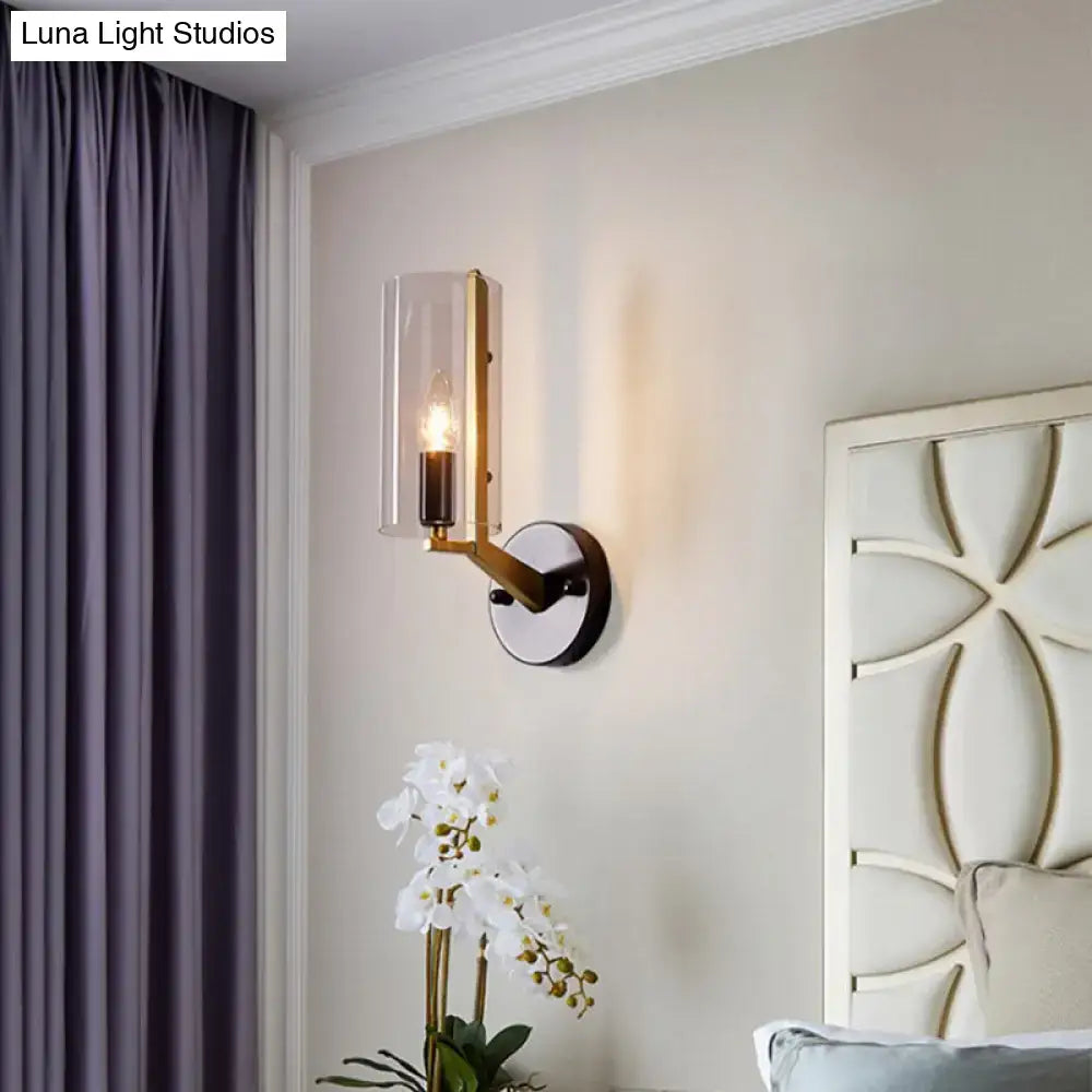 A retro brass and black wall light bedroom transparent glass sconce with a brass arm and clear cylindrical shade