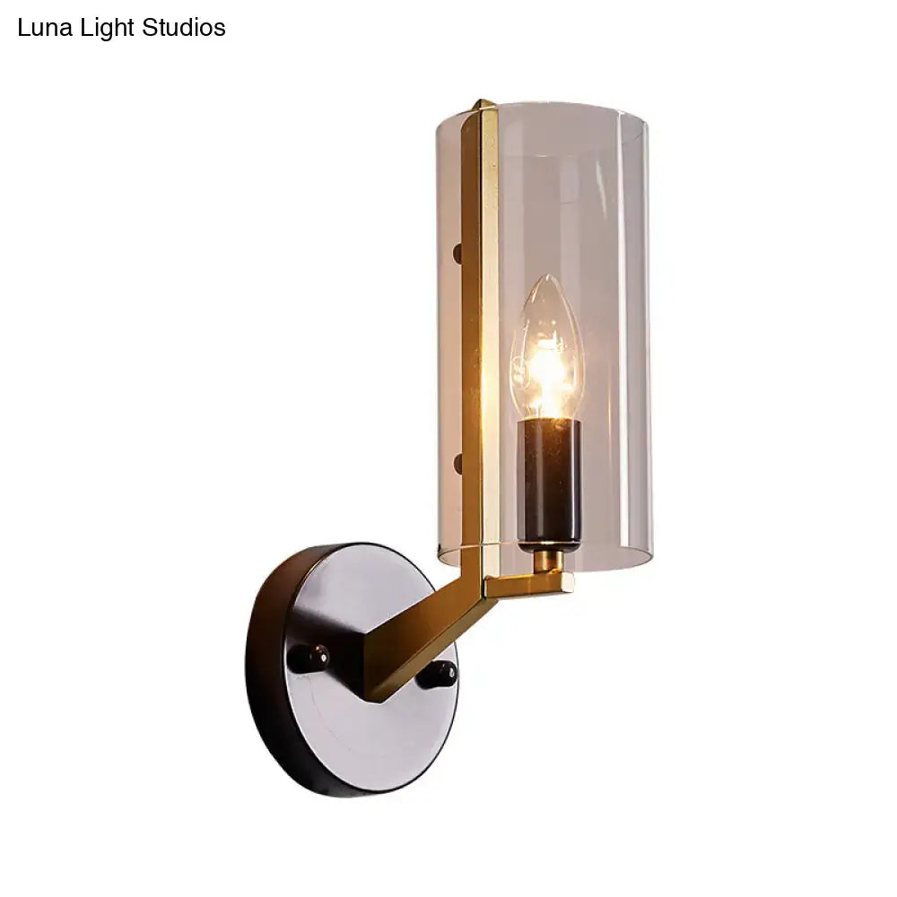 Modern wall light with brass-finished metal frame and transparent glass sconce featuring smoked glass cylinder shade