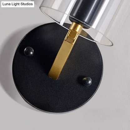Black circular wall light with a gold-toned metal arm and transparent glass sconce for bedroom use
