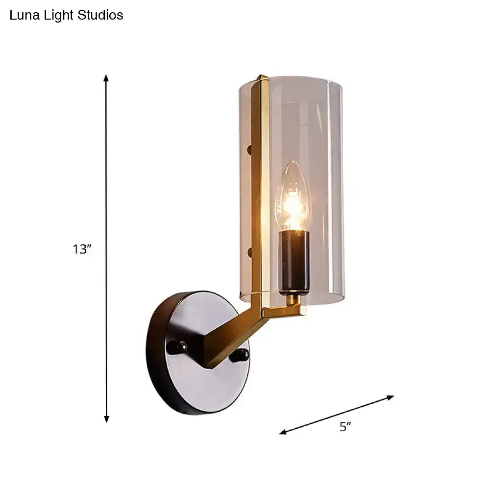 A modern retro brass and black wall light with a brushed brass finish and transparent glass sconce shade