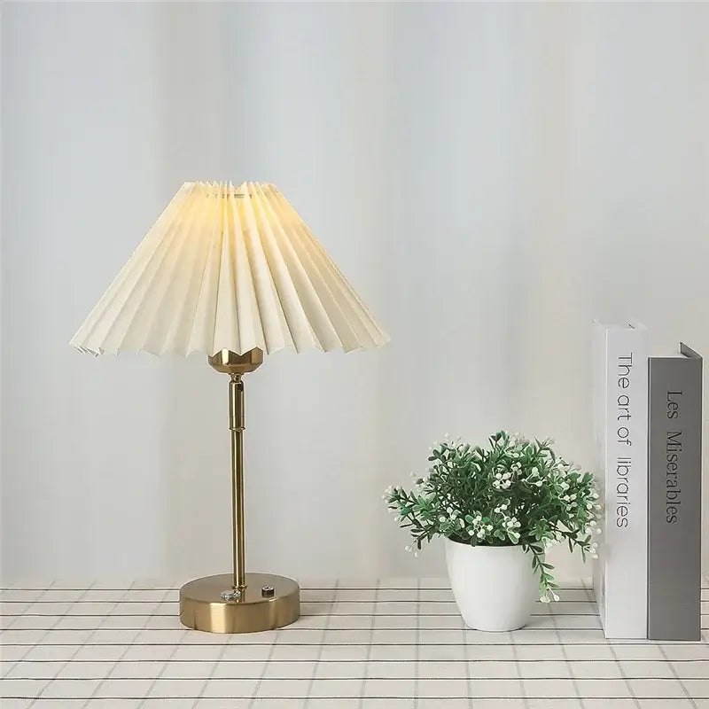 Cream-colored pleated table lamp with brass-finished metal base featuring decorbites adjustable pleated design
