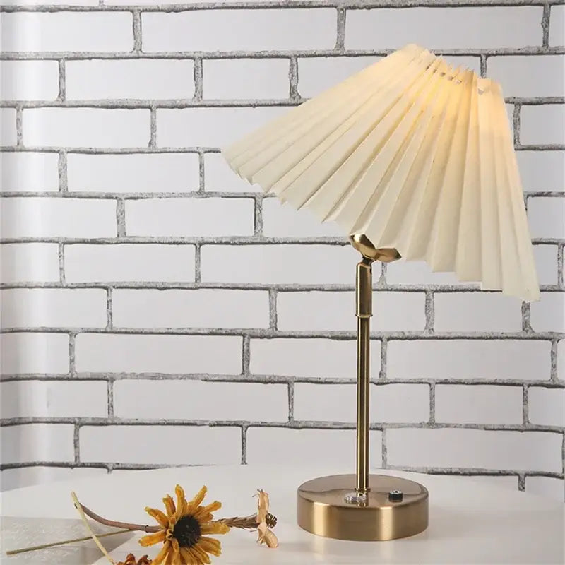 A cream pleated table lamp with brass finish adjustable pleated table stand and circular base for bedroom light