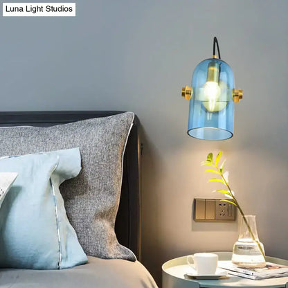 Retro brass cloche sconce light with blue glass and gold-toned hardware for bedroom featuring a smoke gray shade