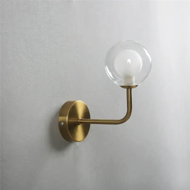 Retro brass curved wall lamp with brass finish and clear glass ball housing an exposed bulb for bedroom decorbites wall lamp
