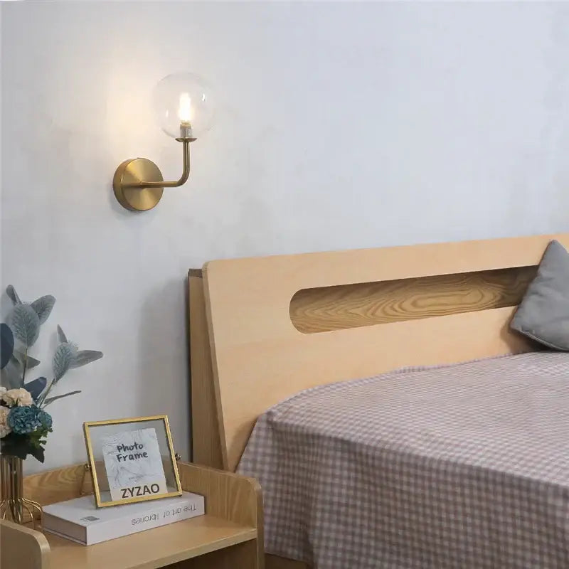 Brass-finished wall lamp featuring a clear glass ball bulb ideal for bedroom decorbites glass ball lighting